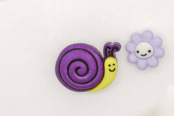 Closeup shot of cute cartoon snail and flower figurines on a white surface