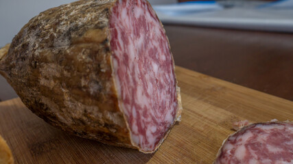 closeup of italian sopressa salami with homemade bread with knife and being cut