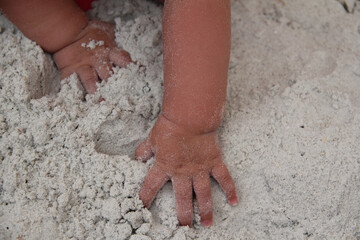 tan baby hands in powder white sand
