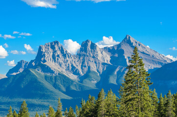 Scenery of high mountain peak over blue sky with white clouds.