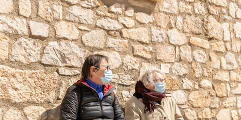 Closeup Portrait of two old woman wearing protective medical face mask during covid-19 pandemic.