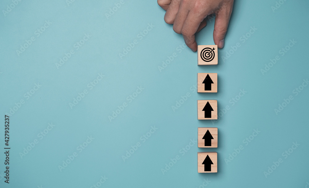 Poster hand putting virtual target board and arrow which print screen on wooden cube. business achievement 