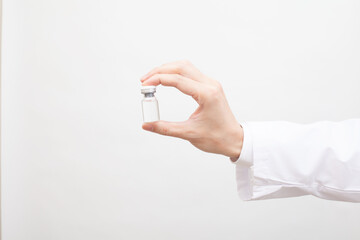 白衣を着た研究員が持つガラス瓶に入った薬