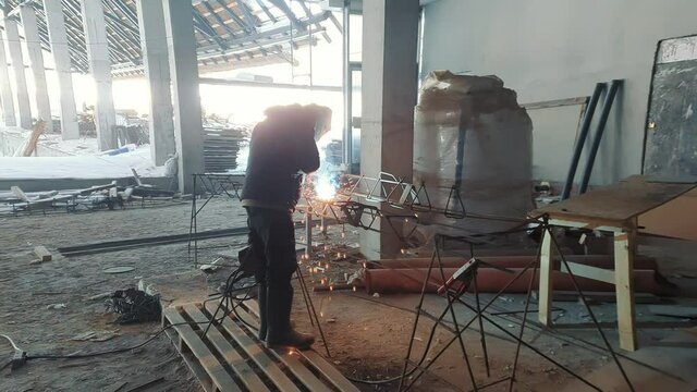 Welder on construction site. The worker welds metal structures.