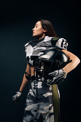 Athletic woman poses in American football uniform with helmet in her hand.