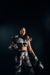 Fototapeta na wymiar Athletic woman poses in American football uniform with helmet and ball in her hands.