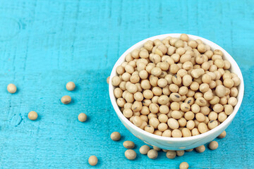 Soybeans in white bowl on blue wooden table. Soy has health benefits because high protein and many other nutrients.