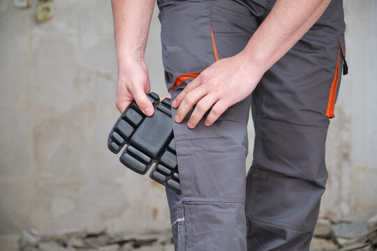 Unrecognizable builder wearing knee protection pads to work in a construction. Safety at work.