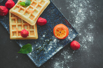 Tasteful Belgian waffles and dried strawberries for breakfast, with sugar powder and syrup