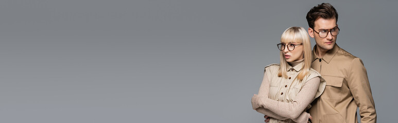 trendy young models in glasses posing isolated on grey, banner