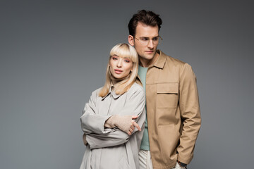 trendy models posing while standing together isolated on grey