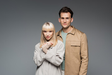 trendy models posing while looking at camera isolated on grey