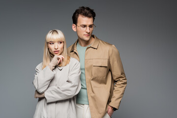 trendy models posing while standing isolated on grey