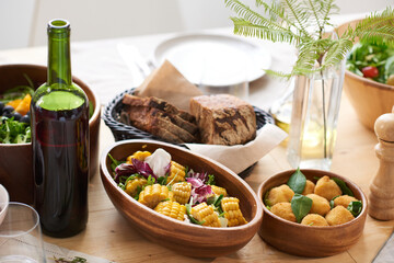 Close-up of different dishes and bottle of wine serving for dinner on dining table