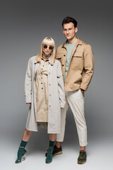 full length of trendy young couple posing on grey