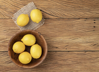 Sicilian lemons in a bowl over wooden table with copy space