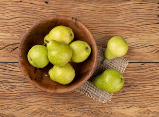 Green pears in a bowl over wooden table