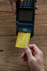 Hands of cafe visitor holding credit card and putting it to the card payment machine,modern bank...