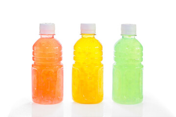 Three plastic bottles with fruit drink of different colors with water droplets freshness, isolated on white