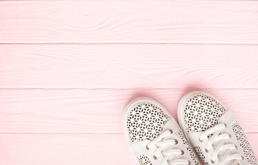 White sneakers on light pink background. Women's shoes. stylish white sneakers.