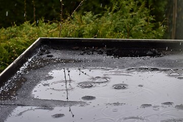 Light rain on a black flat roof against a green background
