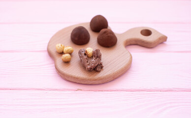Рand made chocolate truffles dusted with cocoa powder on a wooden board.
