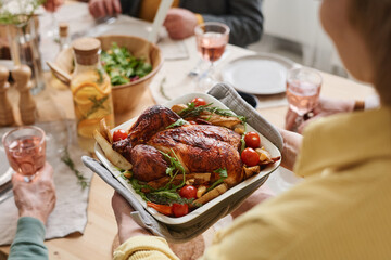 Close-up of woman serving roast chicken for dinner for her family in the dining room