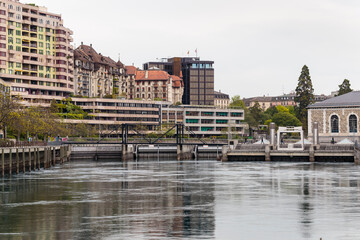 Horizontal soft daylight view of the river Rhone with a footbridge across and buildings in the background, Geneva, Switzerland