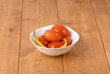 Pickled red tomatoes with chilli in a plate.