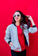 American flat portrait of a smiling young brunette girl with sunglasses on red background