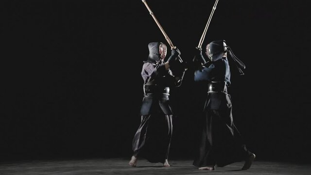 Japanese kendo fighters with bamboo swords on a black background. Slow motion