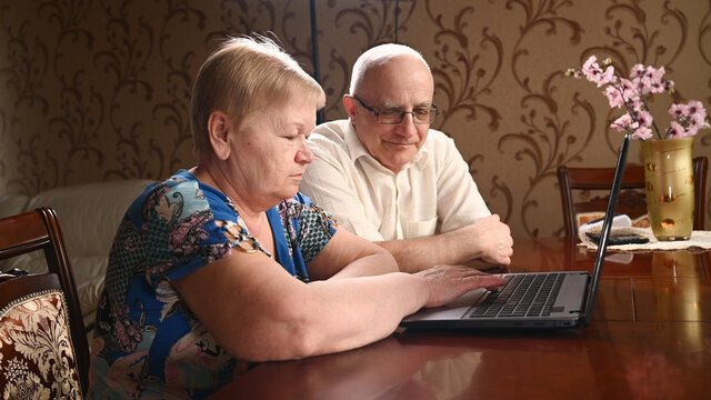 An Elderly Couple Is Sitting At A Computer Looking For Information On The Internet