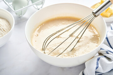 Preparation of dough for home pancakes for Breakfast or for Maslenitsa. Ingredients on the table - wheat flour, eggs, butter, sugar, salt, milk. Recipe step by step. Selective focus.