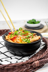 Asian salad with rice noodles, vegetables, mushrooms, chicken and soy sauce. Funchose with white transparent noodles in black plate