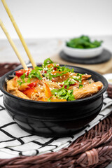 Asian salad with rice noodles, vegetables, mushrooms, chicken and soy sauce. Funchose with white transparent noodles in black plate