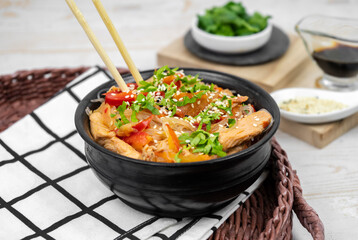 Asian salad with rice noodles, vegetables, mushrooms, chicken and soy sauce. Funchose with white transparent noodles in black plate