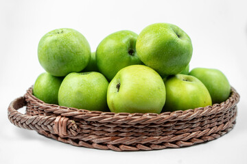 Group of ripe green apples in a basket on white background
