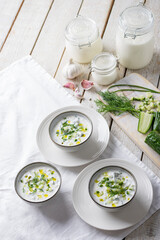 Traditional summer cold soup of homemade yogurt, cucumbers and fresh herbs on a table