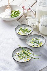 Traditional summer cold soup of homemade yogurt, cucumbers and fresh herbs on a table