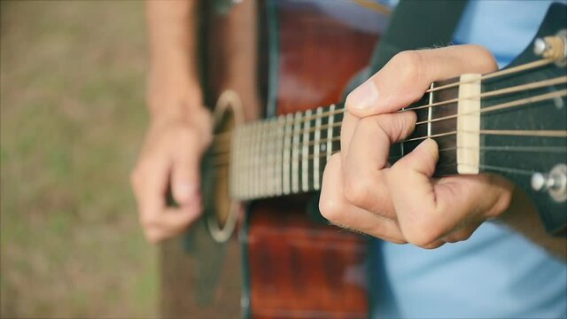 Close-up of the creativ hand's of a man-musician playing the guitar, standing in the street, one writes songs, composes music to the sounds of nature. The man plays the guitar.