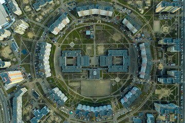 city planning from the sky. the circular architecture of residential buildings surrounds a school with a swimming pool and a football stadium. funny architecture looks like a smile. 4k Aerial