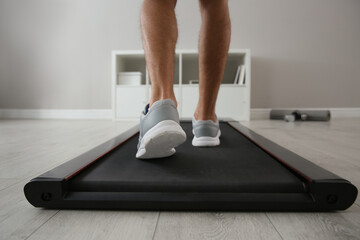 Sporty man training on walking treadmill at home, closeup © New Africa