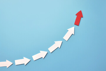 Many white arrows follow one red arrow. Symbol of following the leader straight to the goal