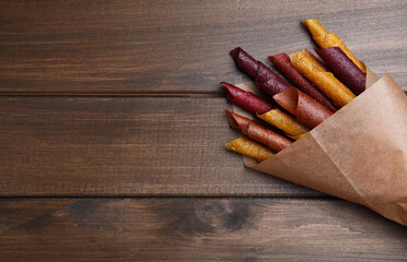 Delicious fruit leather rolls on wooden table, top view. Space for text