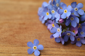 Fototapeta na wymiar Beautiful blue Forget-me-not flowers on wooden table, closeup. Space for text