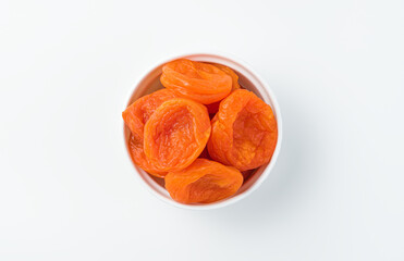 Dried apricot in a transparent cup on a gray background.