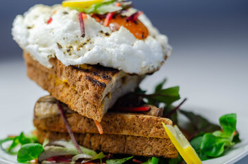 Egg in a cloud on grilled sandwiches with cumberland sausage, tomato and mayonnaise, all served with a fresh salad