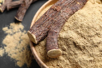 Powder and dried sticks of liquorice root in bowl, closeup