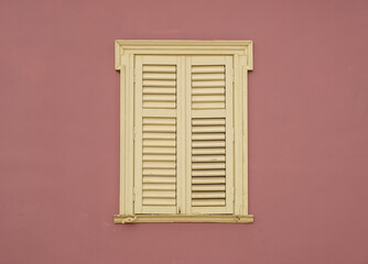 Old fashioned window wooden shutters, closed, on brown color painted wall background.