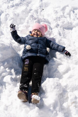 Fototapeta na wymiar Girl lies in the snow in winter